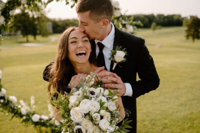 Man Kissing Bride Holding Bouqet